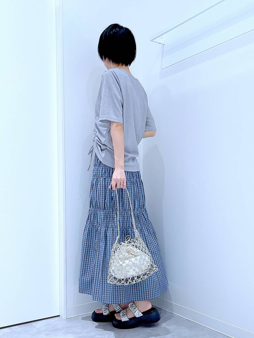 シルバー系のかごバッグ、シルバー系のサンダル、ブルー系のスカートを着用したレディースの夏コーディネートの3枚目の写真