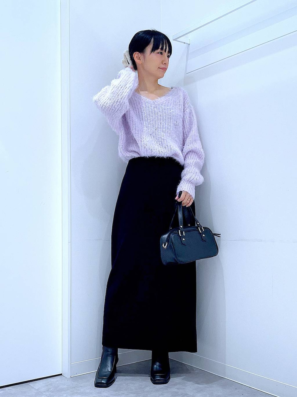 ブラック系のブーツ、ブラック系のショルダーバッグ、ブラック系のスカートを着用したレディースの冬コーディネートの2枚目の写真