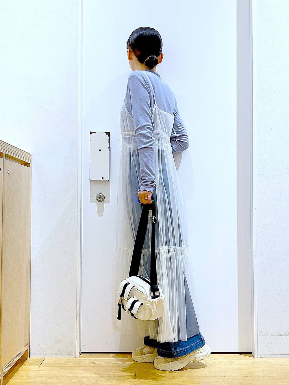 ブルー系のデニムパンツ、ホワイト系のワンピース、ベージュ系のスニーカーを着用したレディースの冬コーディネートの3枚目の写真
