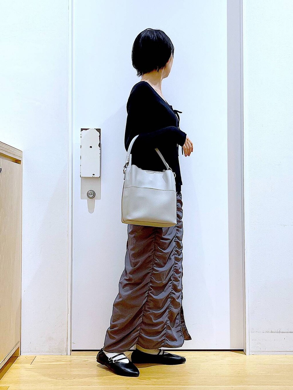ブラック系のパンプス、ブラック系のカーディガン/ボレロ、グレー系のショルダーバッグを着用したレディースの秋コーディネートの4枚目の写真