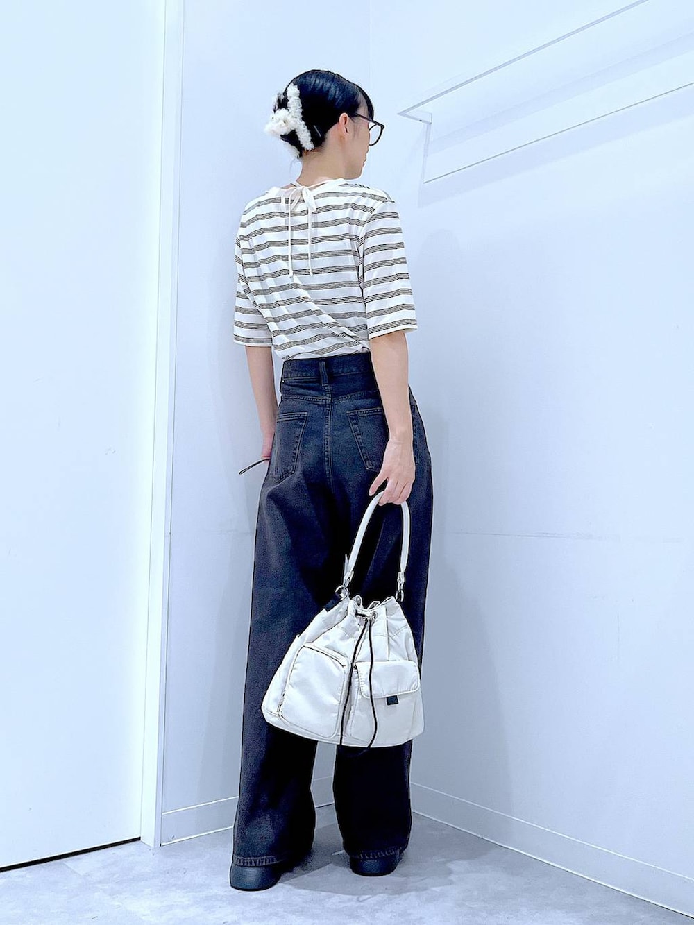 ブラック系のデニムパンツ、ホワイト系のハンドバッグ、ベージュ系のTシャツ/カットソーを着用したレディースの秋コーディネートの5枚目の写真