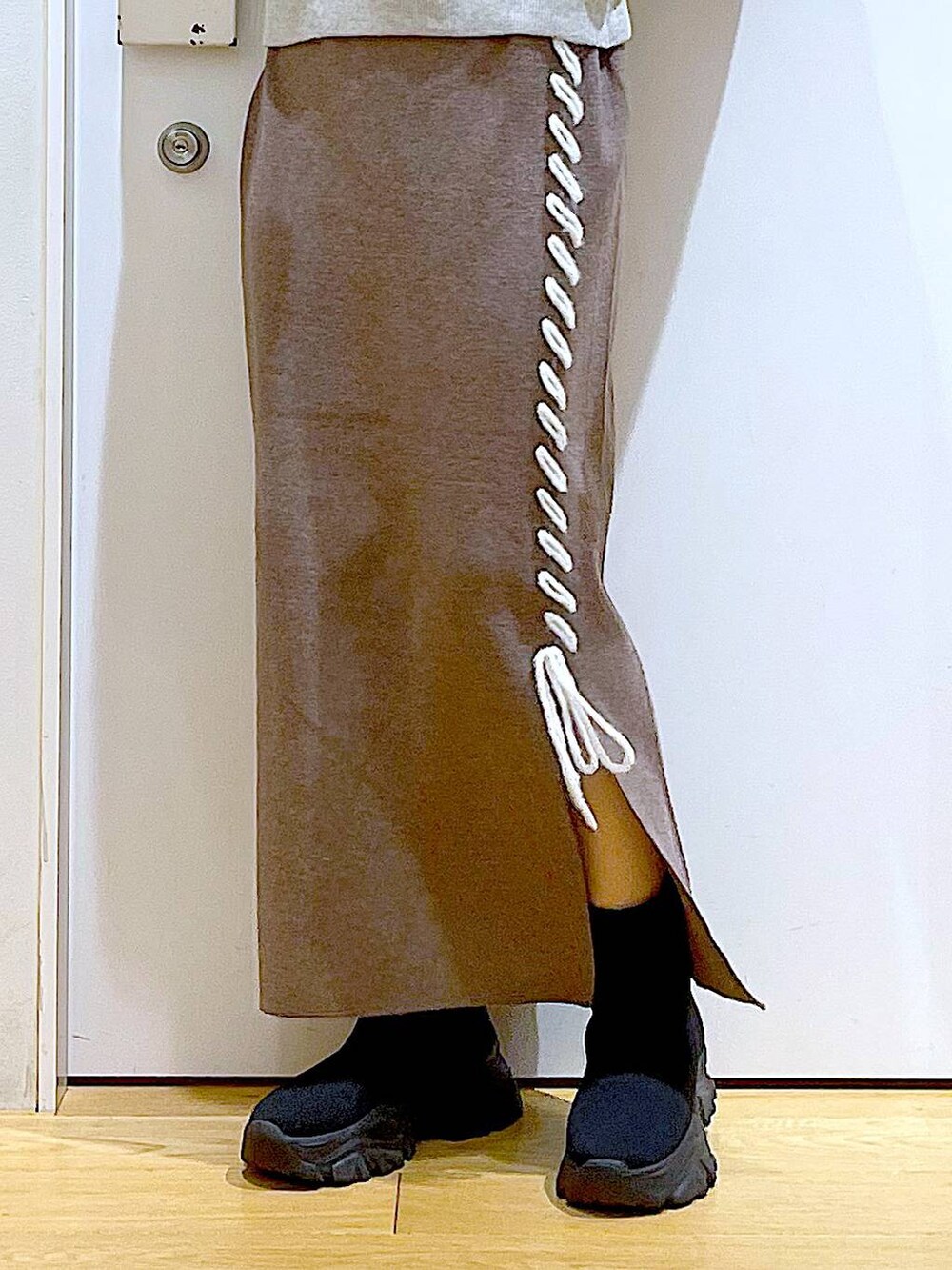 ブラック系のブーツ、ブラウン系のスカート、シルバー系のショルダーバッグを着用したレディースの冬コーディネートの8枚目の写真