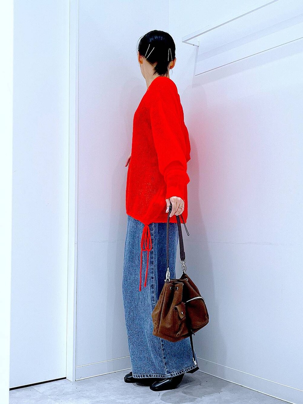 ブラウン系のショルダーバッグ、ブルー系のデニムパンツ、ブラック系のブーツを着用したレディースの秋コーディネートの3枚目の写真