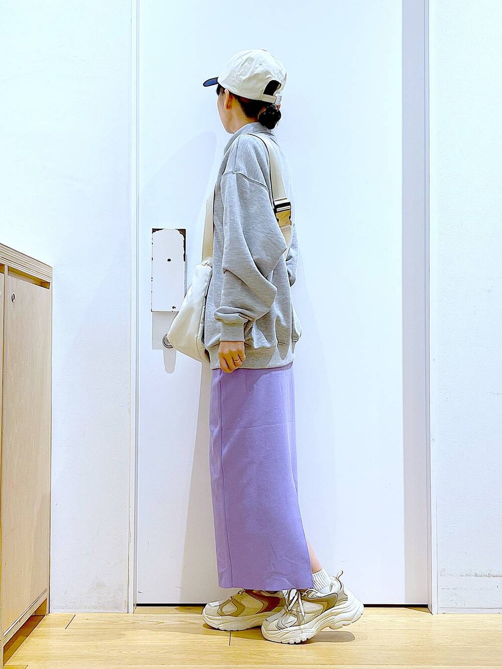 グレー系のスウェット、ベージュ系のスニーカー、ホワイト系のショルダーバッグを着用したレディースの春コーディネートの3枚目の写真