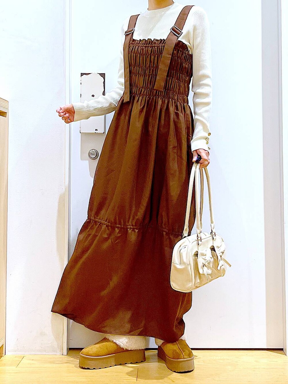 ホワイト系のニット/セーター、ホワイト系のハンドバッグ、ベージュ系のスリッポンを着用したレディースの冬コーディネートの6枚目の写真