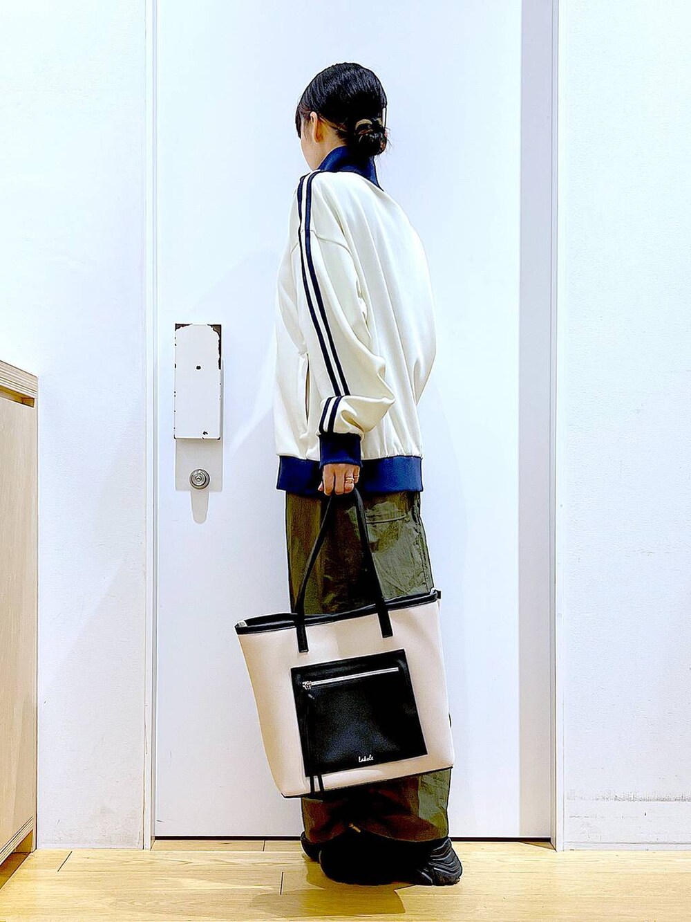 ホワイト系のトートバッグ、ブラック系のブーツ、グリーン系のスカートを着用したレディースの冬コーディネートの3枚目の写真