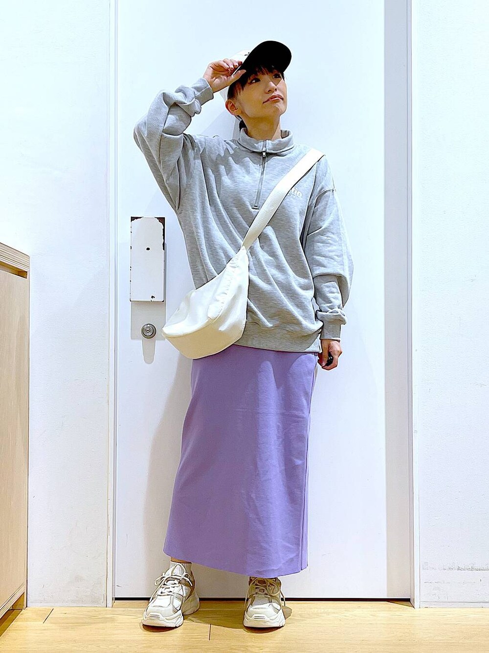 グレー系のスウェット、ベージュ系のスニーカー、ホワイト系のショルダーバッグを着用したレディースの春コーディネートの2枚目の写真