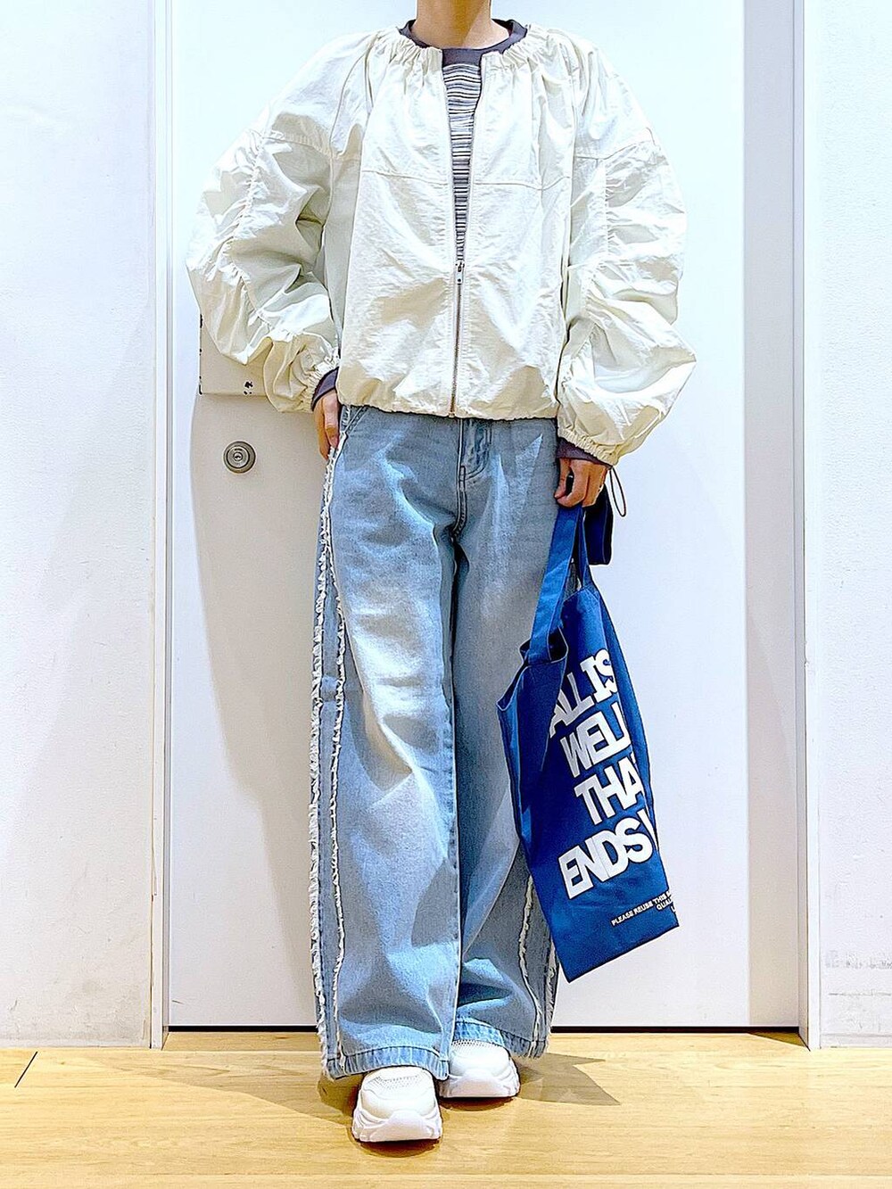 ホワイト系のスニーカー、ブルー系のデニムパンツ、ホワイト系のブルゾンを着用したレディースの春コーディネートの6枚目の写真