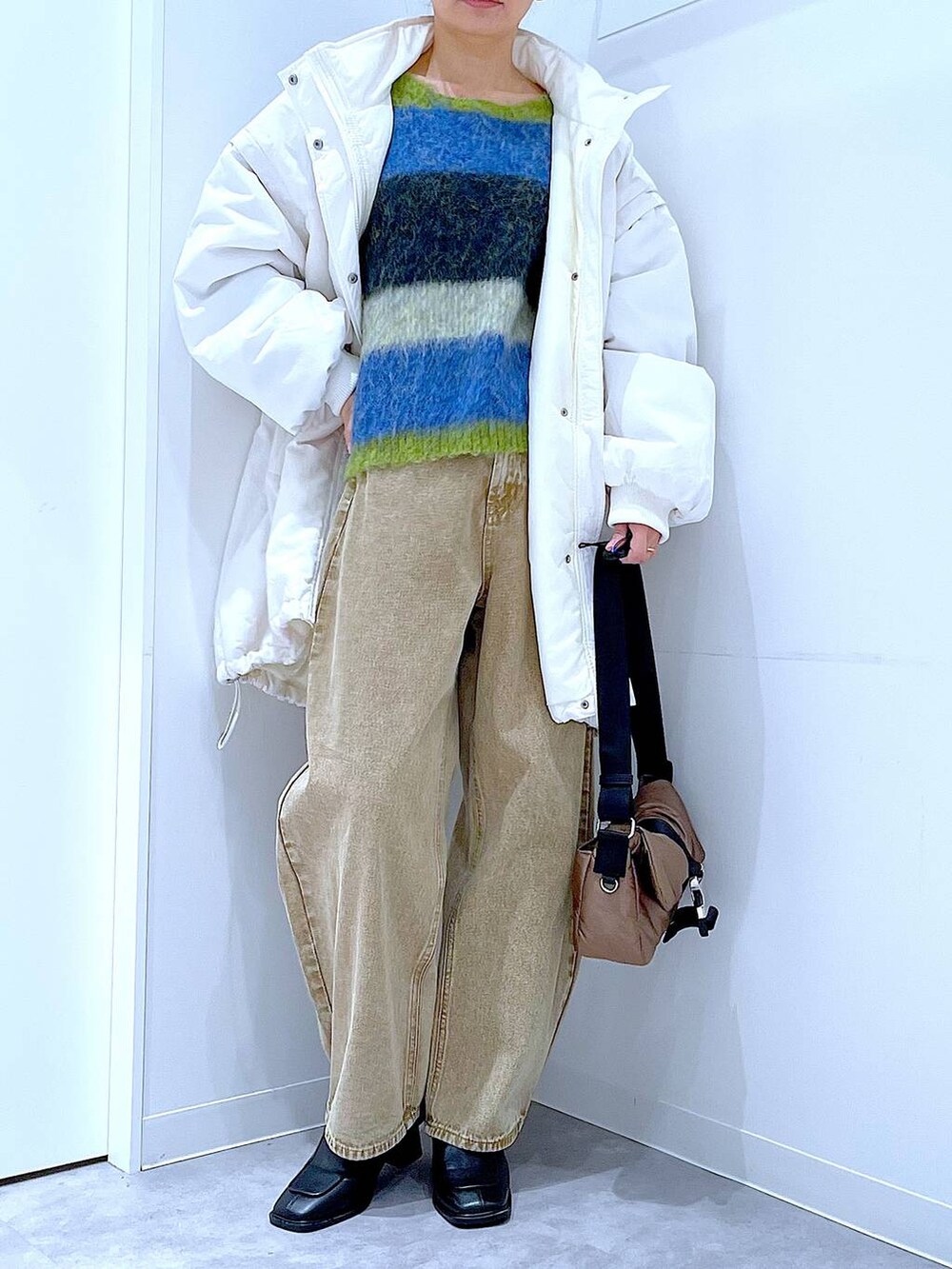 ベージュ系のデニムパンツ、ホワイト系のブルゾン、ブラック系のブーツを着用したレディースの冬コーディネートの6枚目の写真