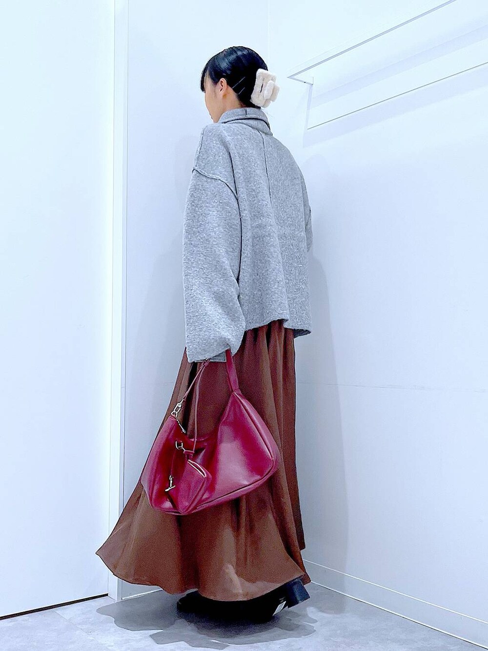 グレー系のブルゾン、ブラック系のブーツ、レッド系のショルダーバッグを着用したレディースの冬コーディネートの3枚目の写真