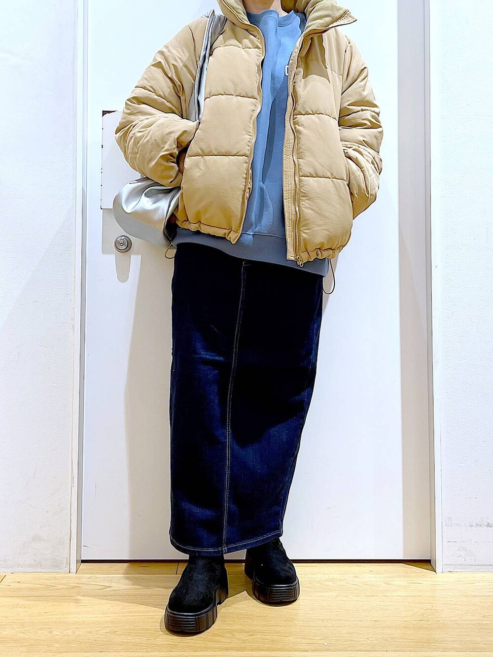 シルバー系のトートバッグ、ベージュ系のナイロンジャケット、ブルー系のデニムスカートを着用したレディースの冬コーディネートの6枚目の写真