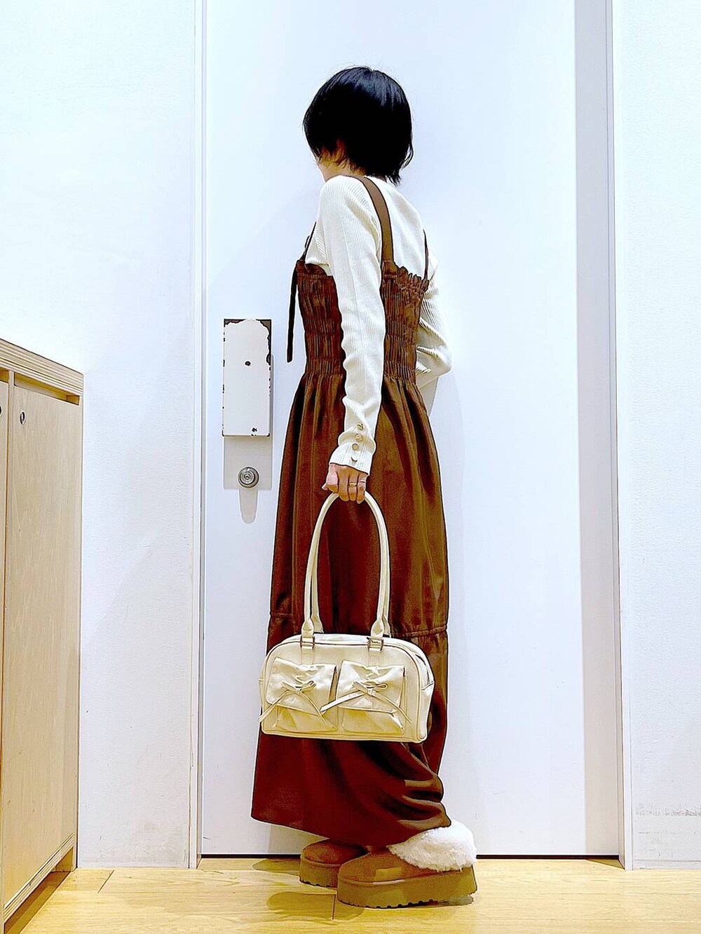 ホワイト系のニット/セーター、ホワイト系のハンドバッグ、ベージュ系のスリッポンを着用したレディースの冬コーディネートの3枚目の写真