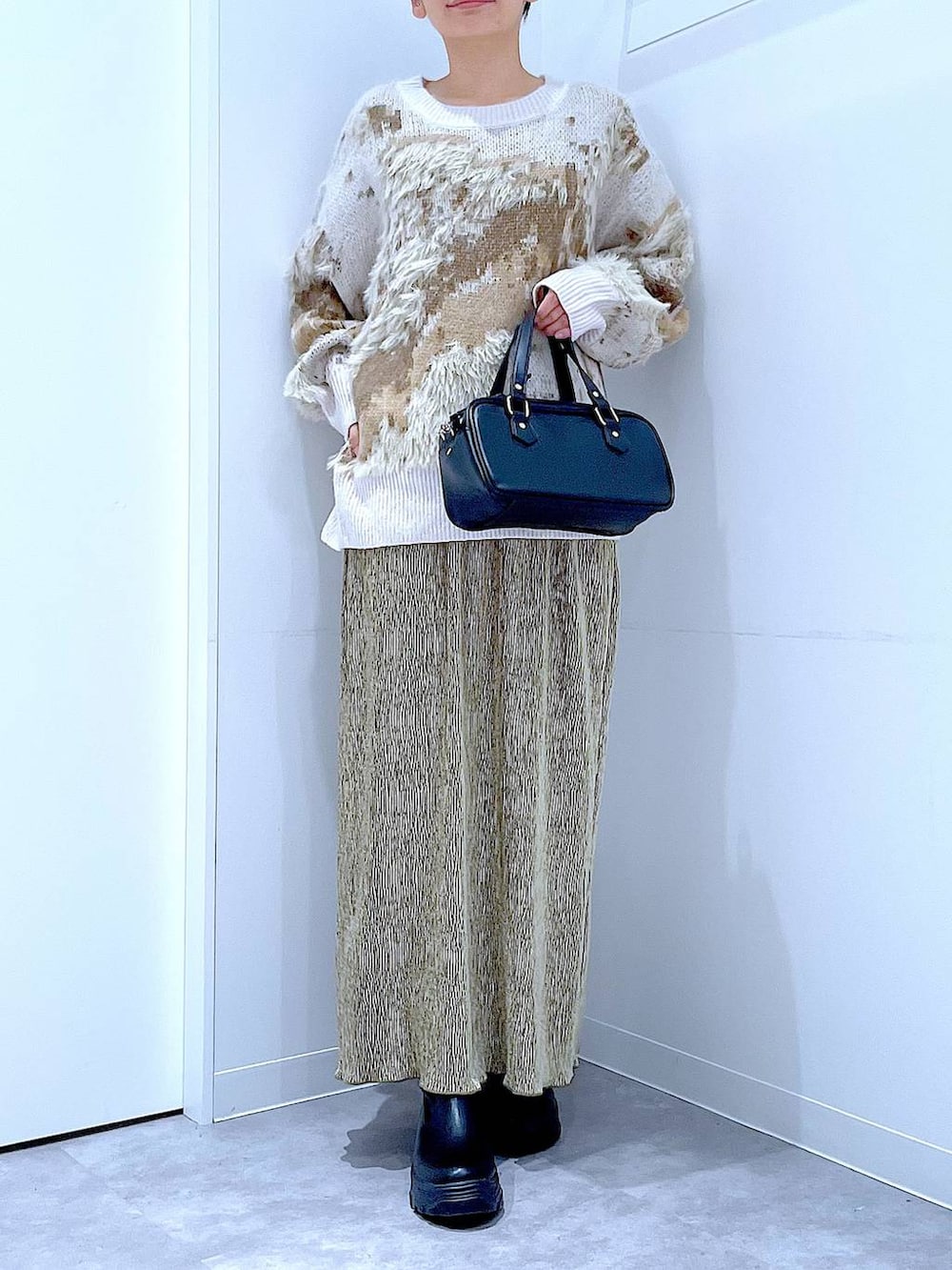 ブラック系のブーツ、ブラック系のショルダーバッグ、グリーン系のスカートを着用したレディースの冬コーディネートの6枚目の写真