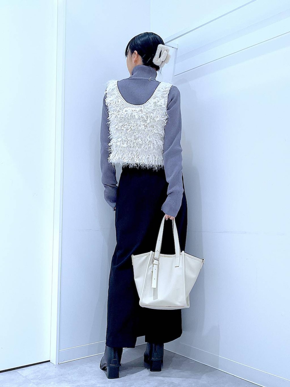 ブラック系のスカート、ブラック系のブーツ、グレー系のニット/セーターを着用したレディースの冬コーディネートの5枚目の写真