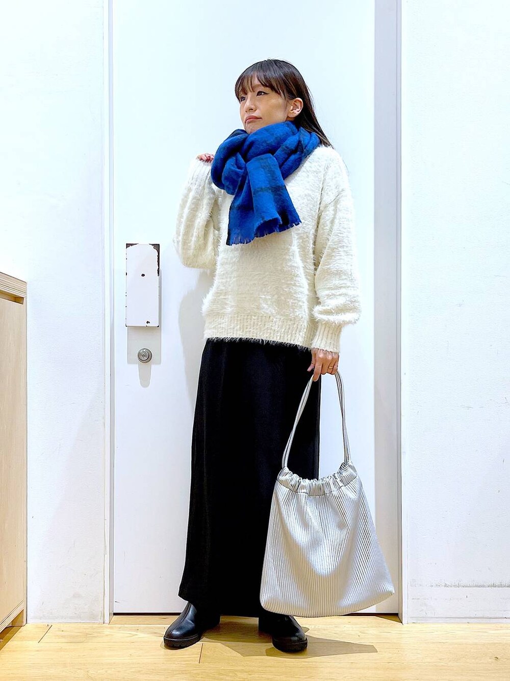 ブラック系のブーツ、シルバー系のトートバッグ、ベージュ系のニット/セーターを着用したレディースの冬コーディネートの2枚目の写真