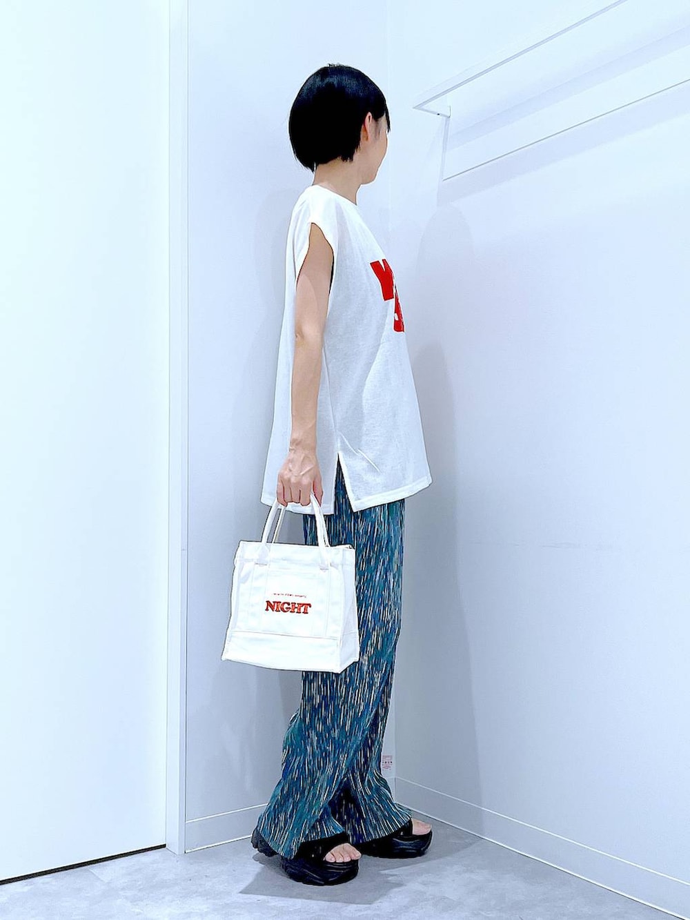 ブラック系のスニーカー、ホワイト系のTシャツ/カットソー、ホワイト系のトートバッグを着用したレディースの夏コーディネートの4枚目の写真