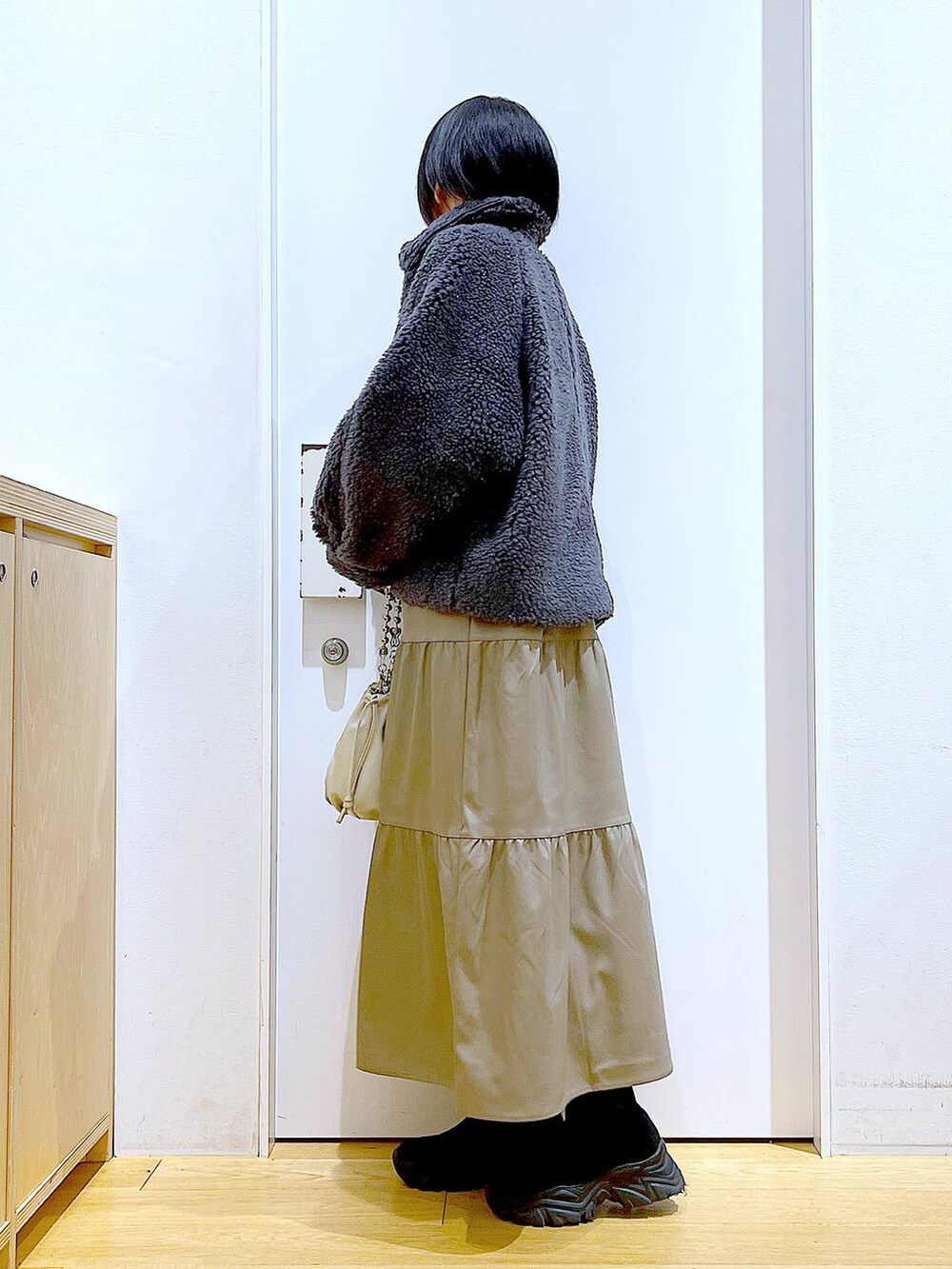 ベージュ系のショルダーバッグ、ブラック系のブーツ、ブラウン系のワンピースを着用したレディースの冬コーディネートの3枚目の写真