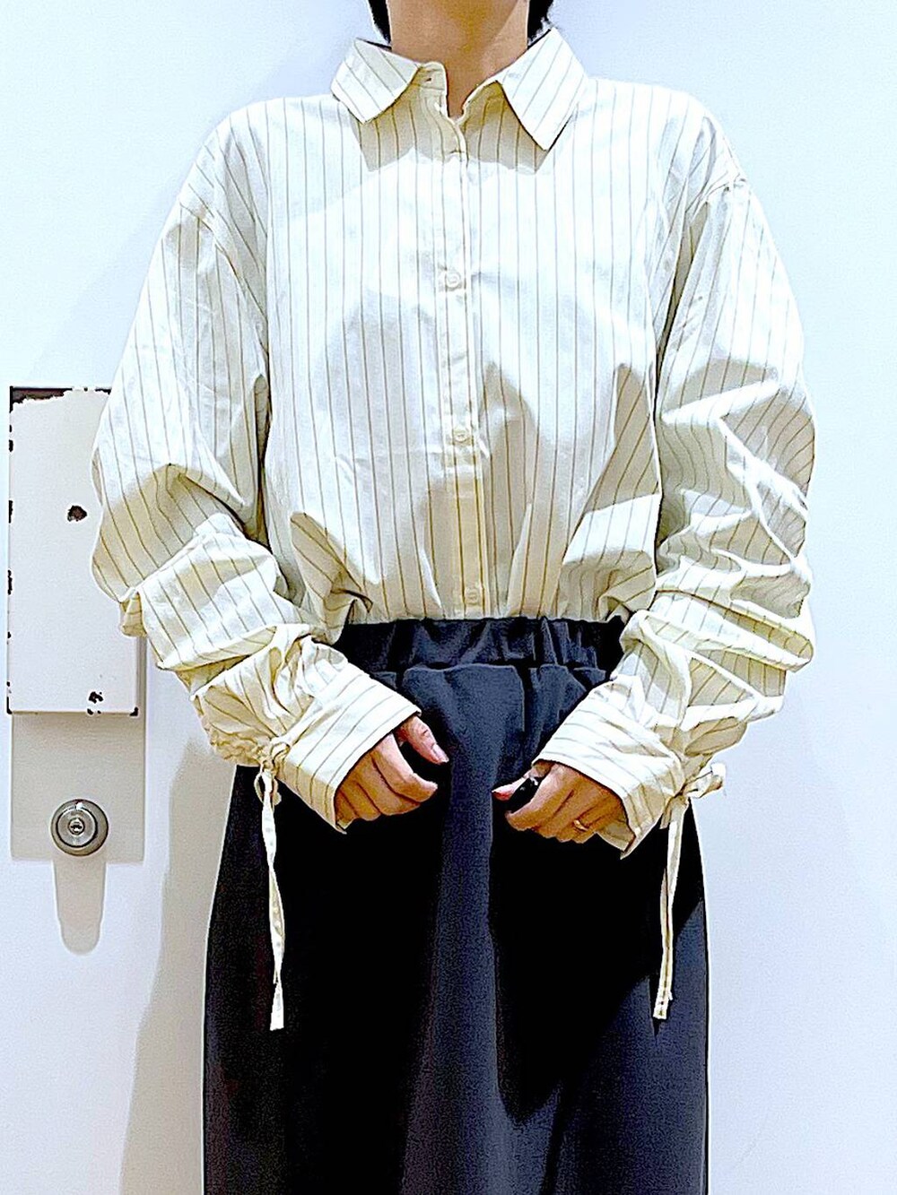 ホワイト系のパンプス、ベージュ系のシャツ/ブラウス、グレー系のスカートを着用したレディースの春コーディネートの7枚目の写真