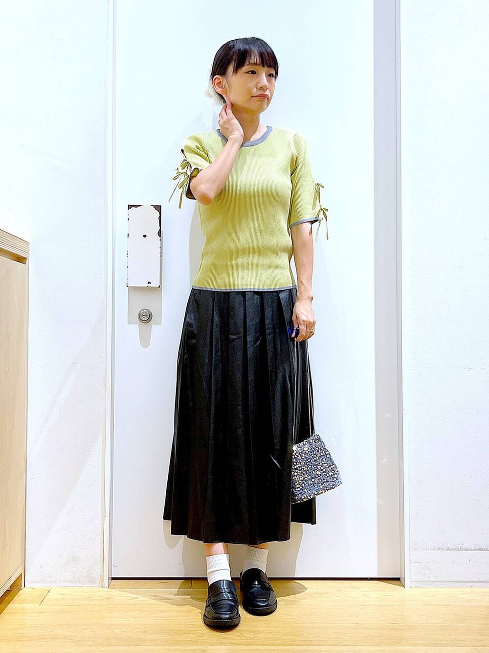 グレー系のショルダーバッグ、ブラック系のローファー、イエロー系のニット/セーターを着用したレディースの秋コーディネートの2枚目の写真