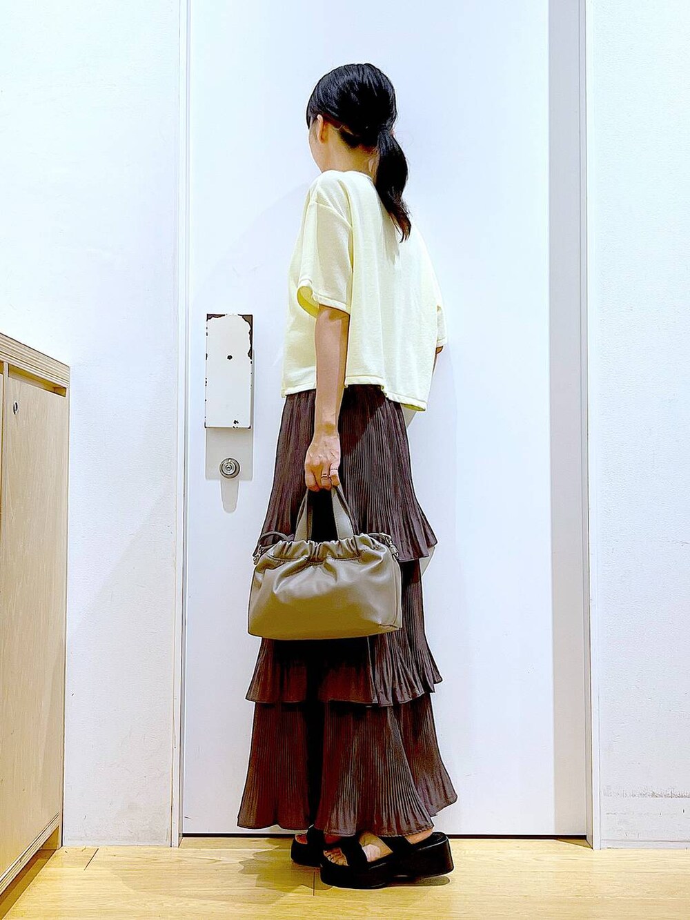 ブラウン系のスカート、ブラウン系のショルダーバッグ、ブラック系のサンダルを着用したレディースの秋コーディネートの3枚目の写真