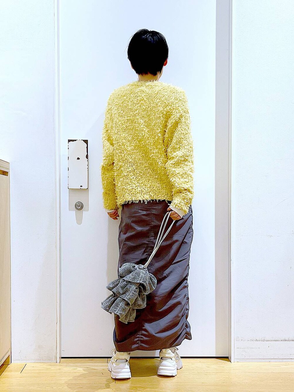 シルバー系のショルダーバッグ、グレー系のスカート、ホワイト系のスニーカーを着用したレディースの春コーディネートの5枚目の写真