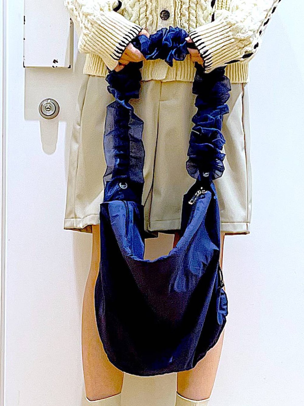 ベージュ系のニット/セーター、ブルー系のショルダーバッグ、ベージュ系のブーツを着用したレディースの冬コーディネートの9枚目の写真