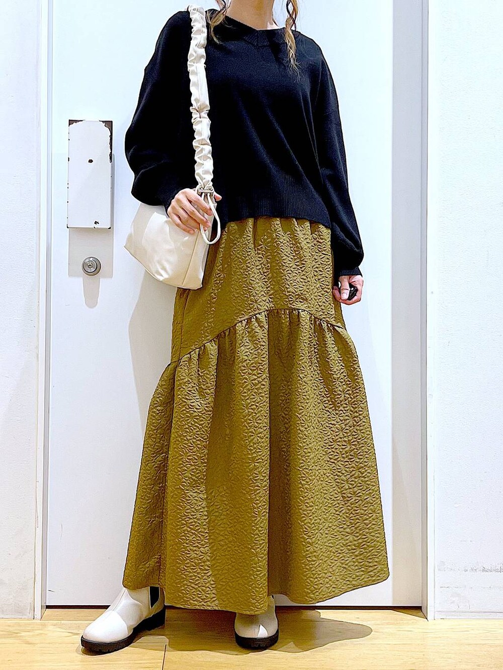 ホワイト系のショルダーバッグ、ベージュ系のブーツ、ブラック系のニット/セーターを着用したレディースの冬コーディネートの7枚目の写真