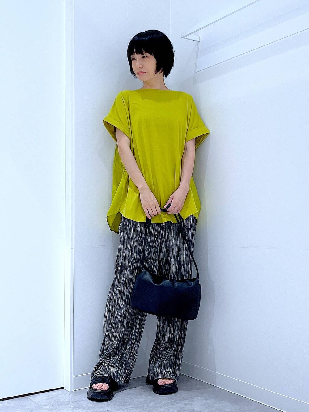 ブラック系のスニーカー、ブラック系のショルダーバッグ、グリーン系のTシャツ/カットソーを着用したレディースの夏コーディネートの2枚目の写真