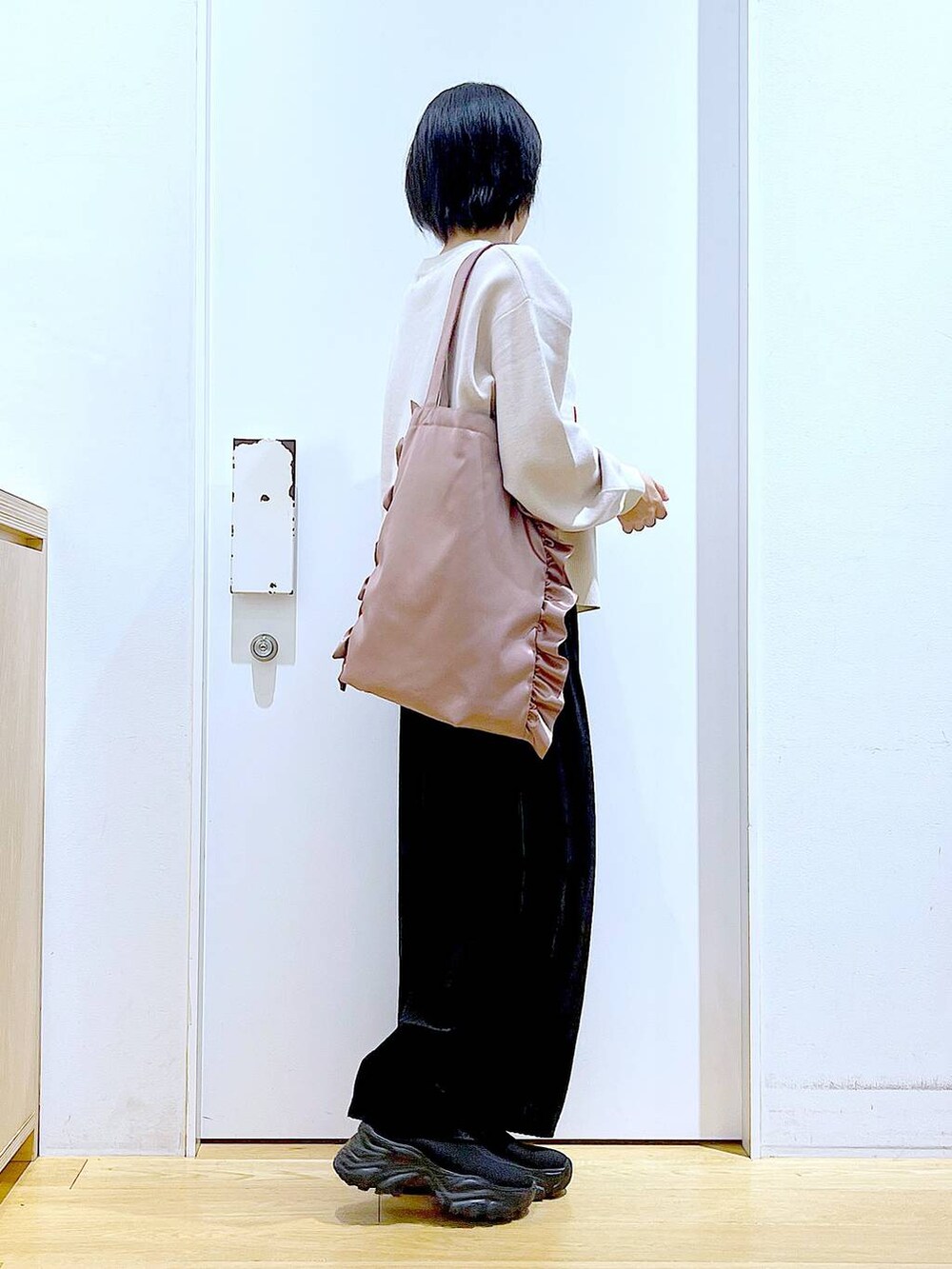 ブラック系のブーツ、ブラック系のスカート、ピンク系のトートバッグを着用したレディースの冬コーディネートの4枚目の写真