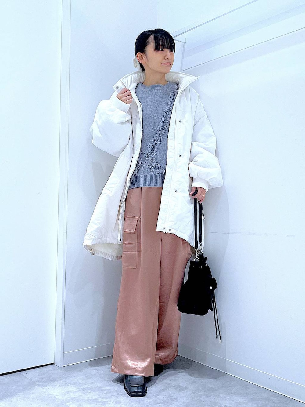 ホワイト系のブルゾン、ブラック系のショルダーバッグ、ブラック系のブーツを着用したレディースの冬コーディネートの2枚目の写真