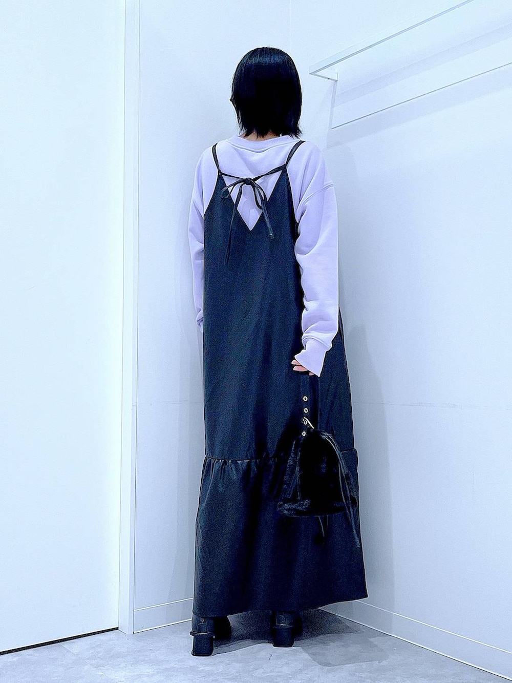 ブラック系のハンドバッグ、ブラック系のブーツ、パープル系のスウェットを着用したレディースの冬コーディネートの5枚目の写真