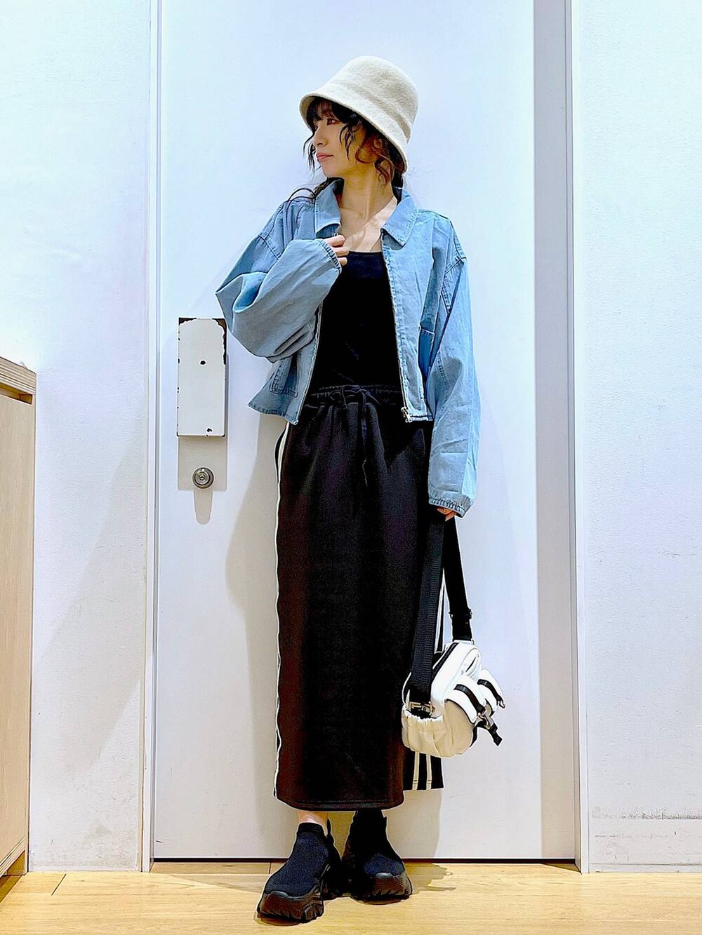 ブルー系のデニムジャケット、ブラック系のスカート、ブラック系のスニーカーを着用したレディースの春コーディネートの2枚目の写真