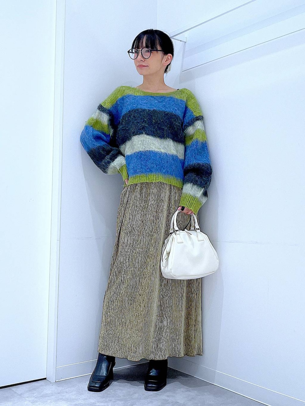 ブラック系のブーツ、ホワイト系のショルダーバッグ、ブルー系のニット/セーターを着用したレディースの冬コーディネートの2枚目の写真