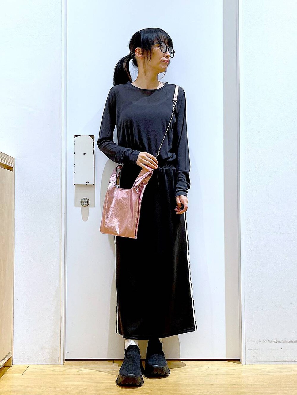 ブラック系のスカート、ピンク系のショルダーバッグ、ブラック系のスニーカーを着用したレディースの春コーディネートの2枚目の写真