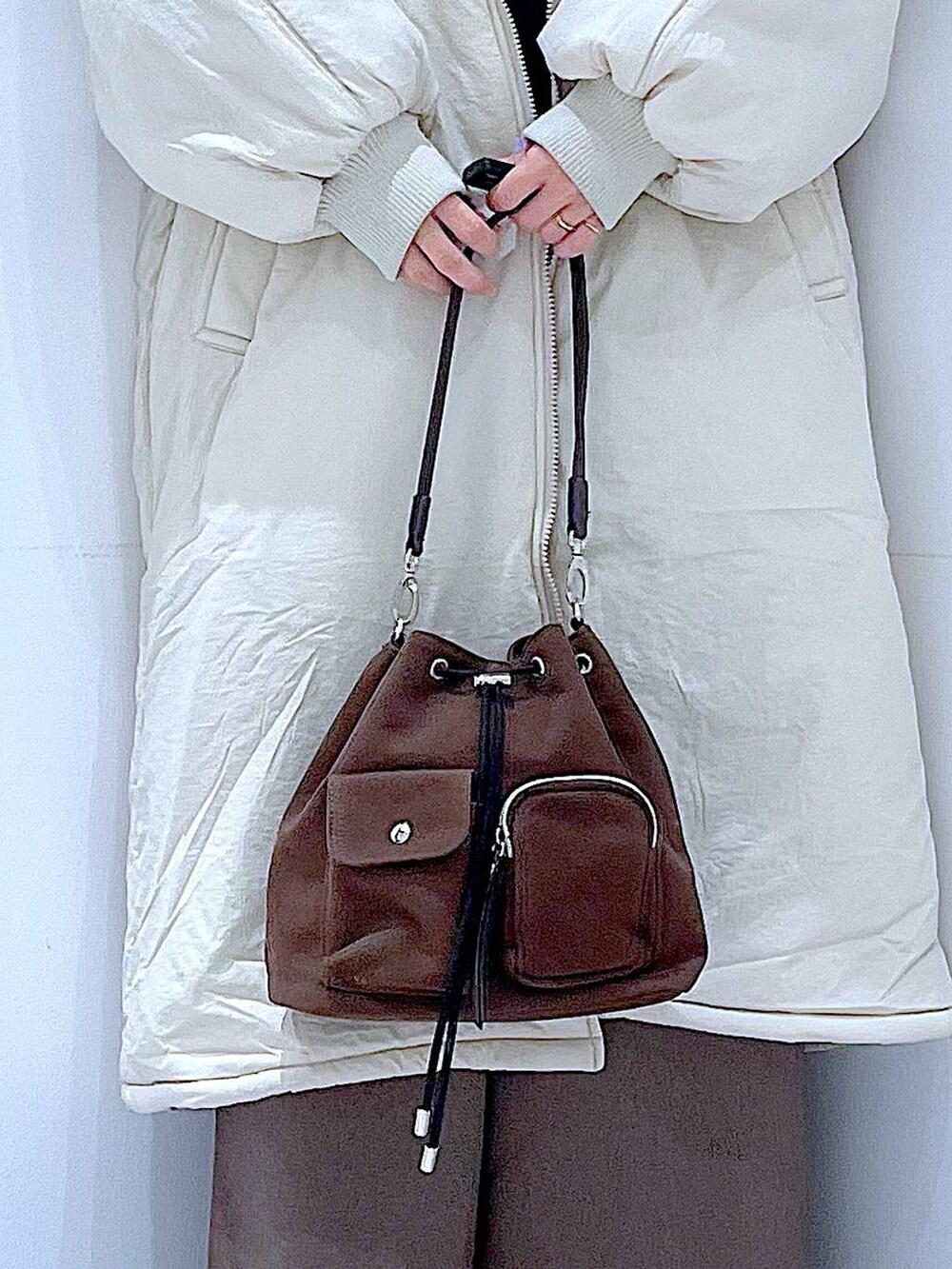 ホワイト系のブルゾン、ブラウン系のショルダーバッグ、ブラック系のブーツを着用したレディースの冬コーディネートの9枚目の写真