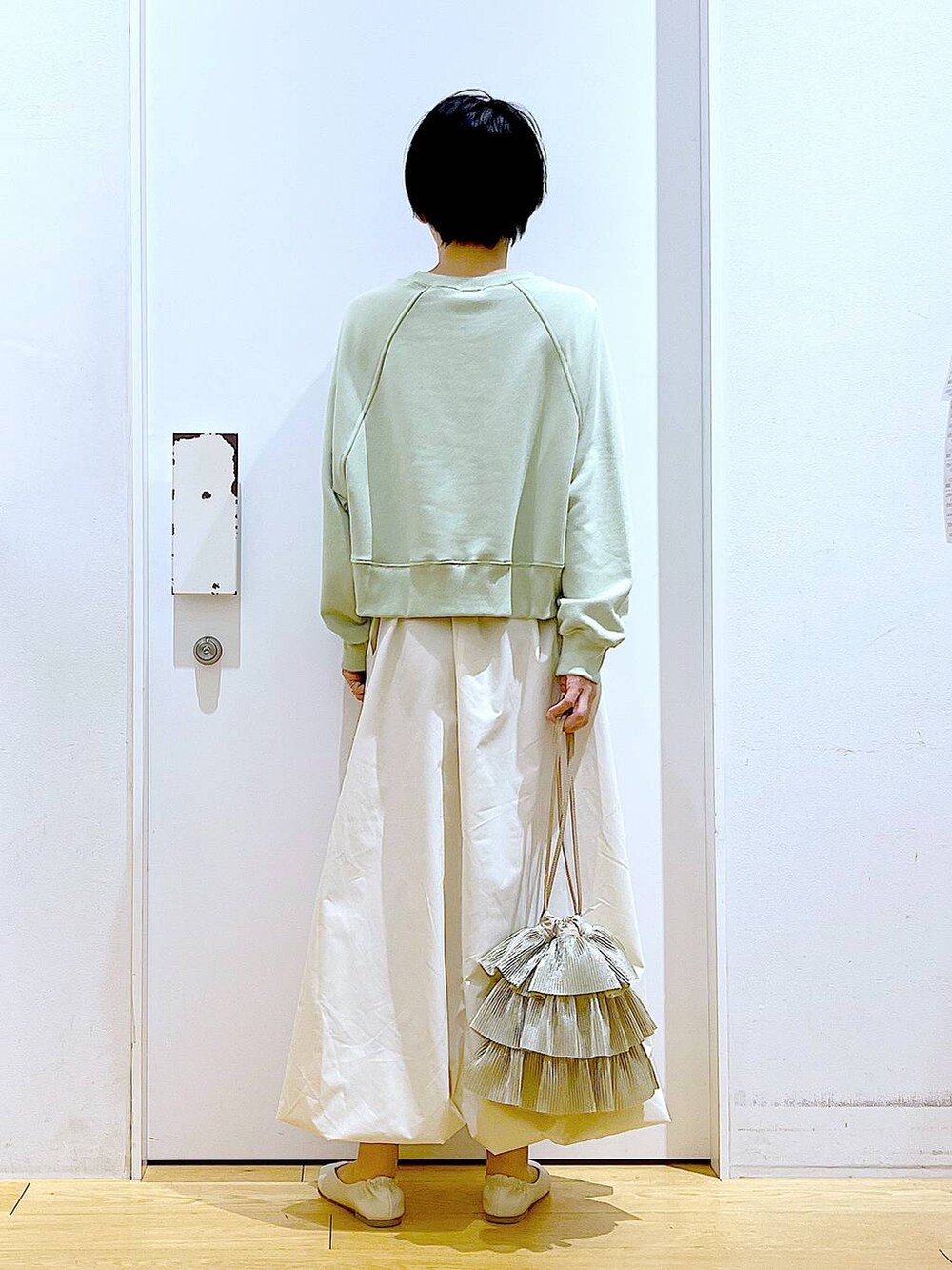 ホワイト系のパンプス、ベージュ系のショルダーバッグ、グリーン系のスウェットを着用したレディースの春コーディネートの5枚目の写真