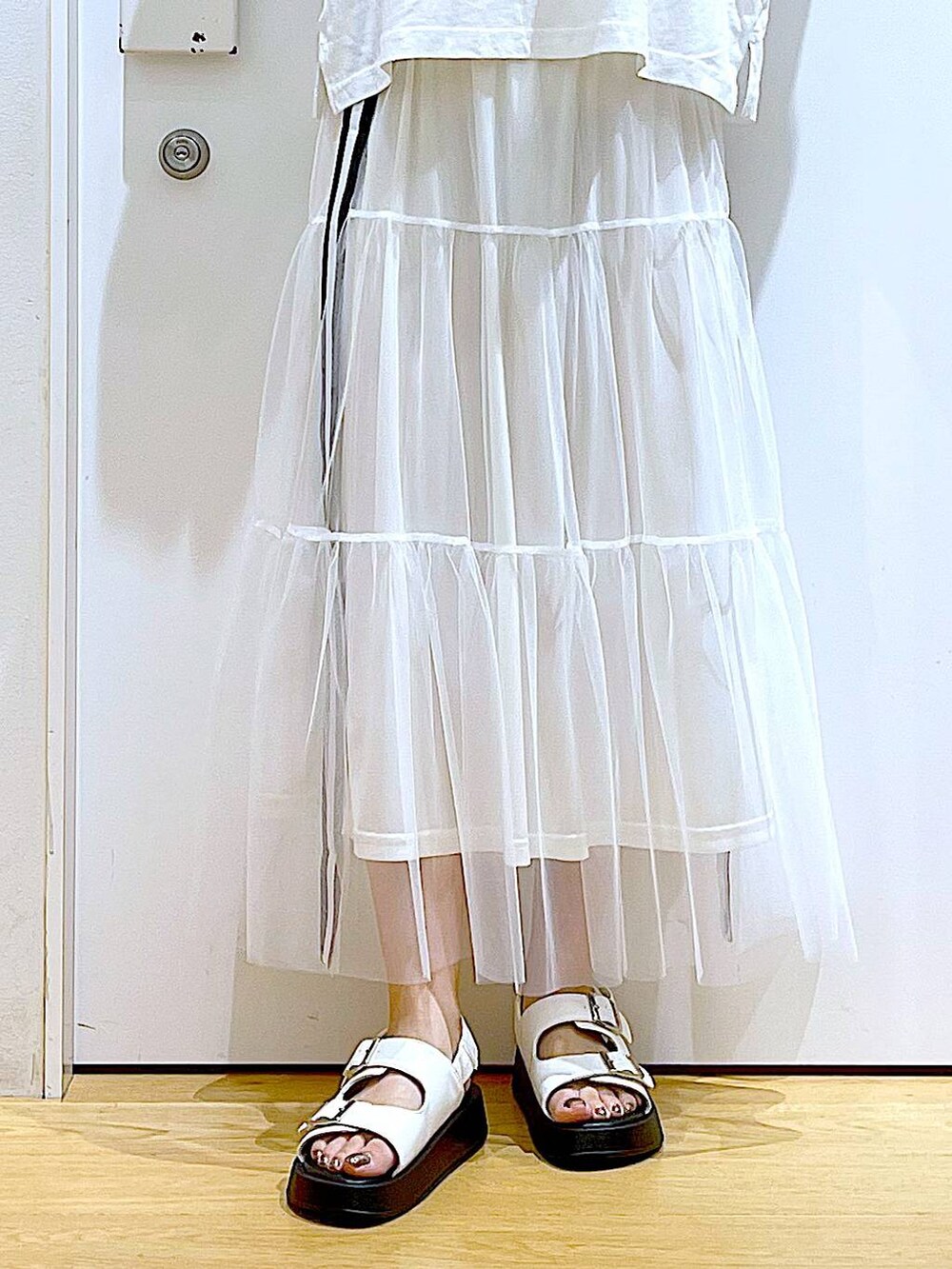 ホワイト系のサンダル、ホワイト系のスカート、ホワイト系のTシャツ/カットソーを着用したレディースの夏コーディネートの8枚目の写真