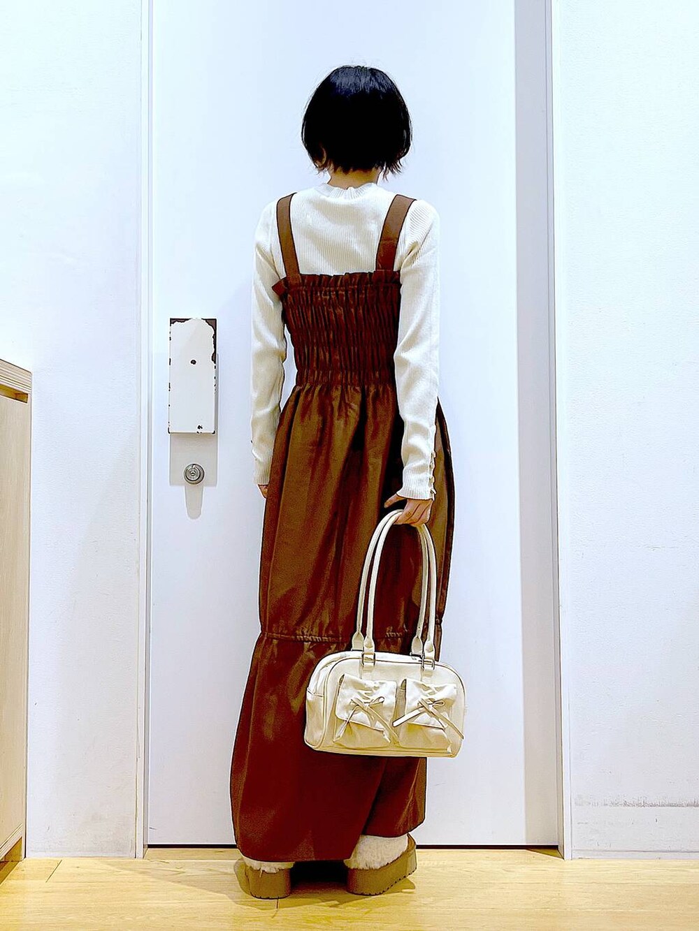 ホワイト系のニット/セーター、ホワイト系のハンドバッグ、ベージュ系のスリッポンを着用したレディースの冬コーディネートの5枚目の写真