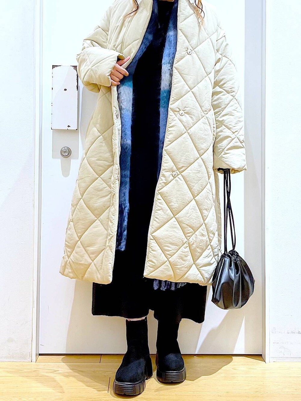 ブラック系のショルダーバッグ、ブラック系のブーツ、ベージュ系のノーカラーコートを着用したレディースの冬コーディネートの6枚目の写真