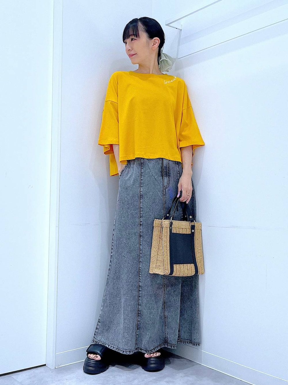 ベージュ系のショルダーバッグ、ブラック系のサンダル、オレンジ系のTシャツ/カットソーを着用したレディースの夏コーディネートの2枚目の写真