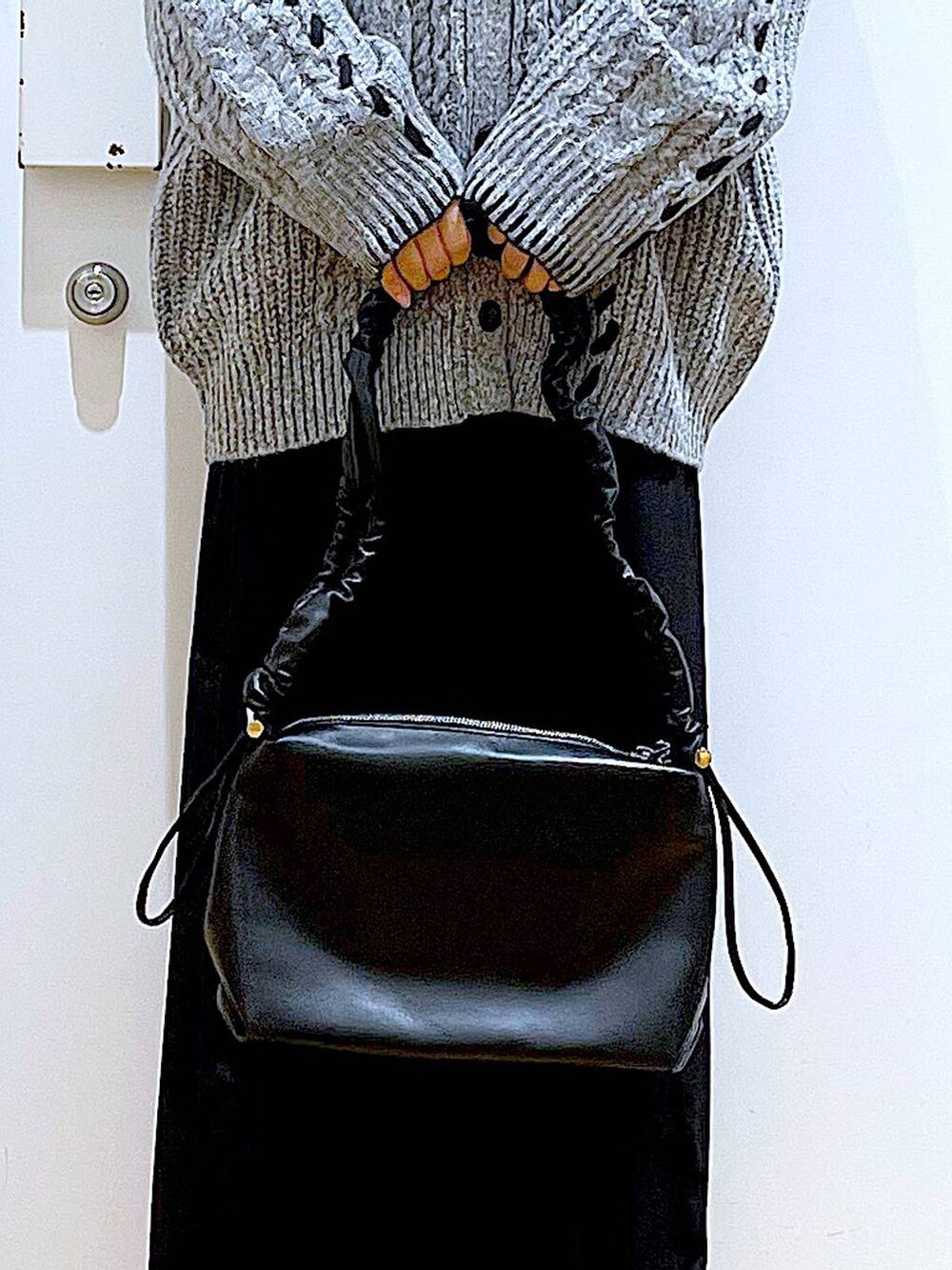 ブラック系のニット/セーター、ブラック系のブーツ、ブラック系のショルダーバッグを着用したレディースの冬コーディネートの9枚目の写真