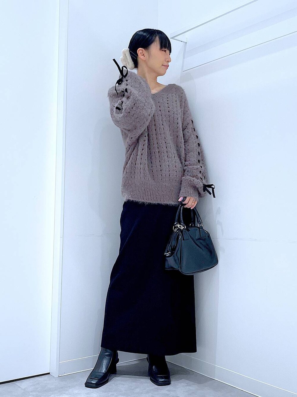 ブラック系のブーツ、ブラック系のショルダーバッグ、ベージュ系のニット/セーターを着用したレディースの冬コーディネートの2枚目の写真