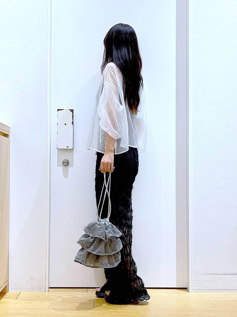 シルバー系のショルダーバッグ、ブラック系のニット/セーター、ブラック系のサンダルを着用したレディースの夏コーディネートの3枚目の写真