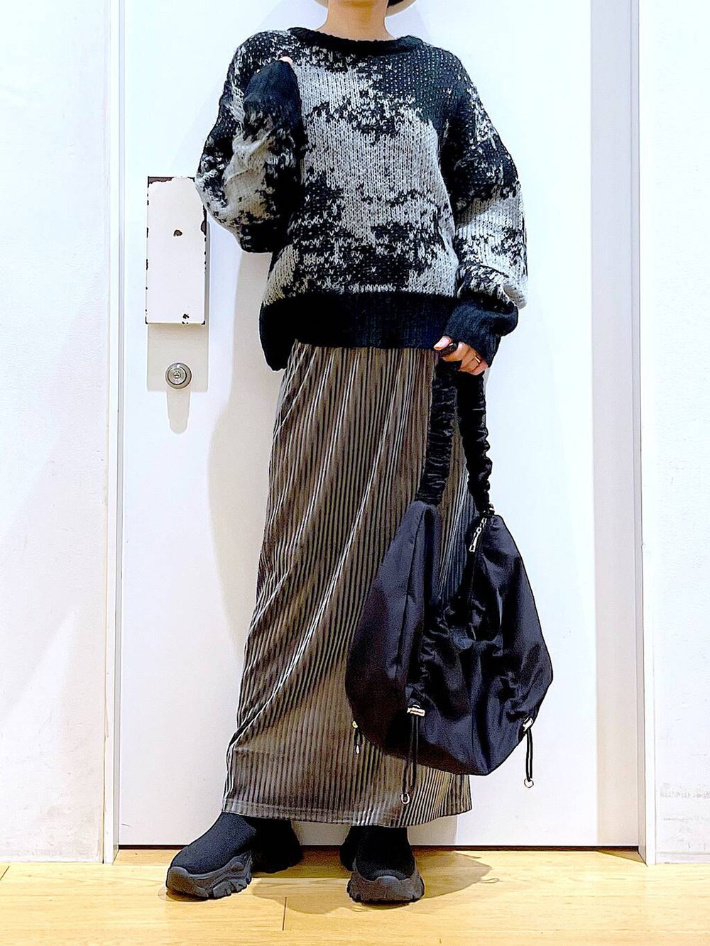 ブラック系のショルダーバッグ、グレー系のスカート、ブラック系のブーツを着用したレディースの冬コーディネートの6枚目の写真