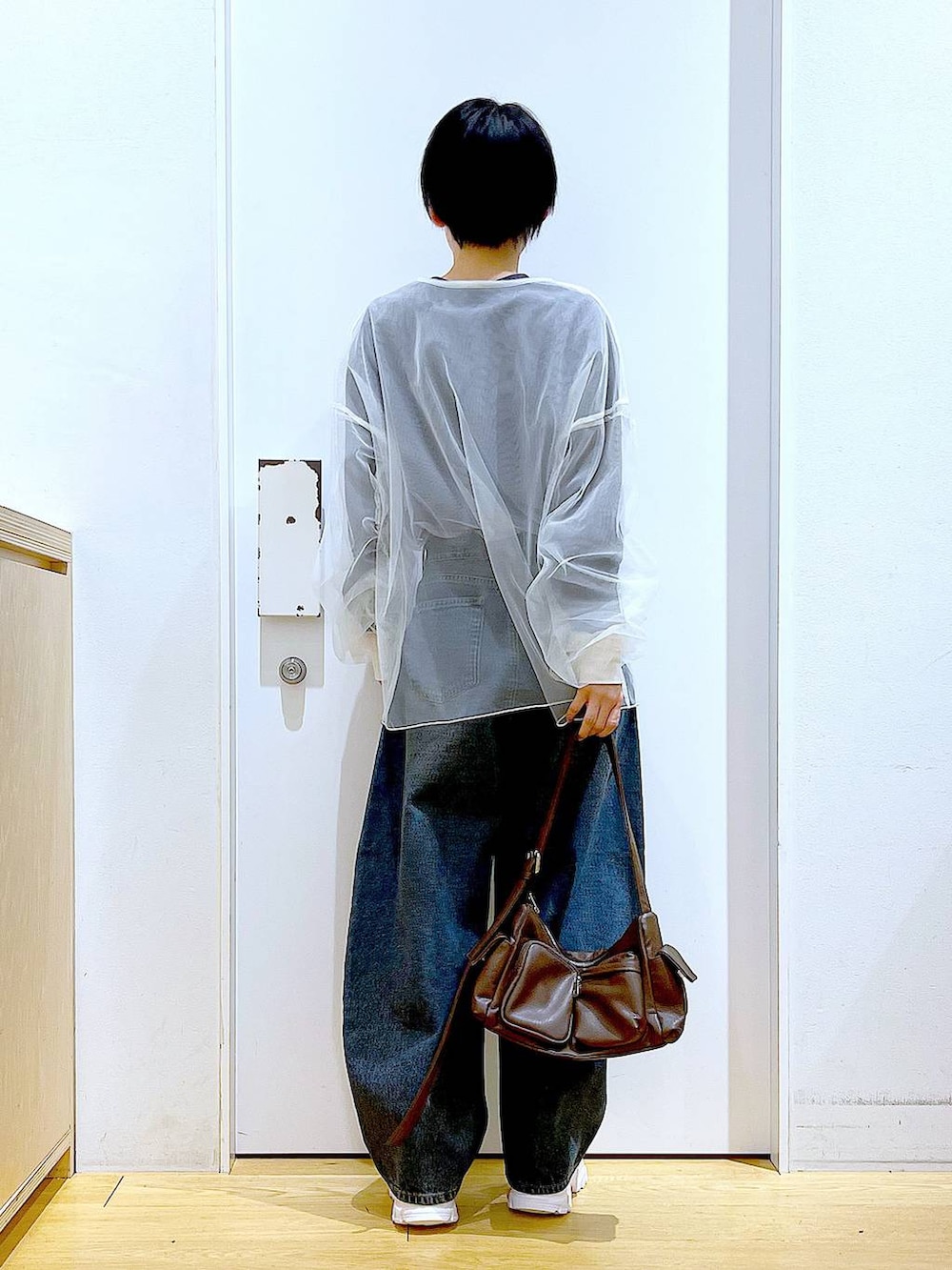 ブルー系のデニムパンツ、ブラウン系のショルダーバッグ、ホワイト系のスニーカーを着用したレディースの春コーディネートの5枚目の写真
