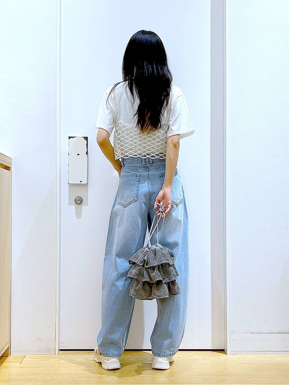 シルバー系のショルダーバッグ、ベージュ系のサンダル、ブルー系のデニムパンツを着用したレディースの夏コーディネートの5枚目の写真