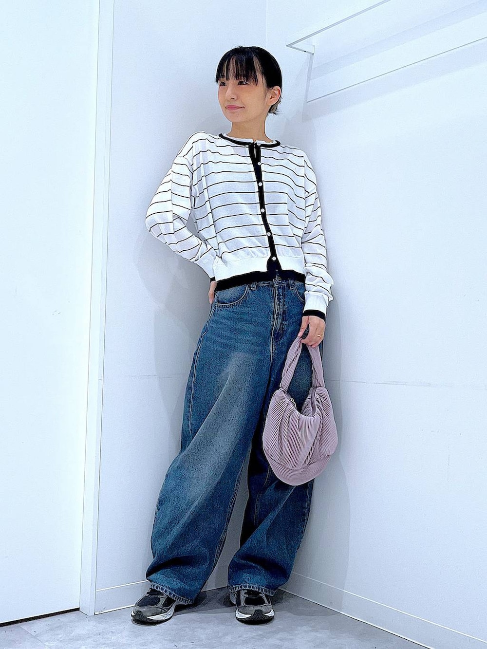 ブルー系のデニムパンツ、ピンク系のショルダーバッグ、ホワイト系のカーディガン/ボレロを着用したレディースの春コーディネートの2枚目の写真