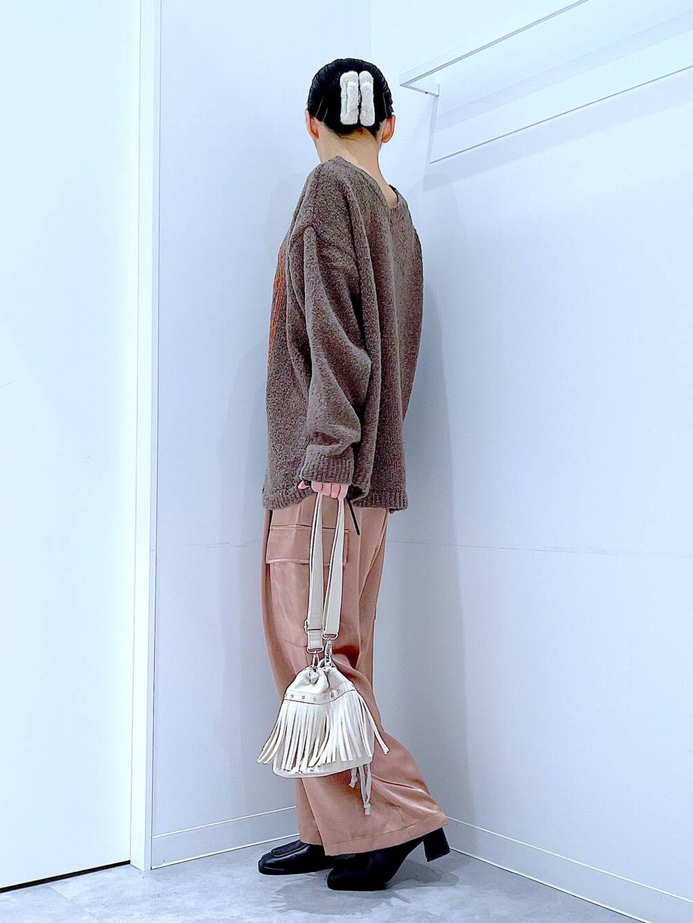 ブラウン系のニット/セーター、ブラック系のブーツ、ホワイト系のショルダーバッグを着用したレディースの冬コーディネートの3枚目の写真