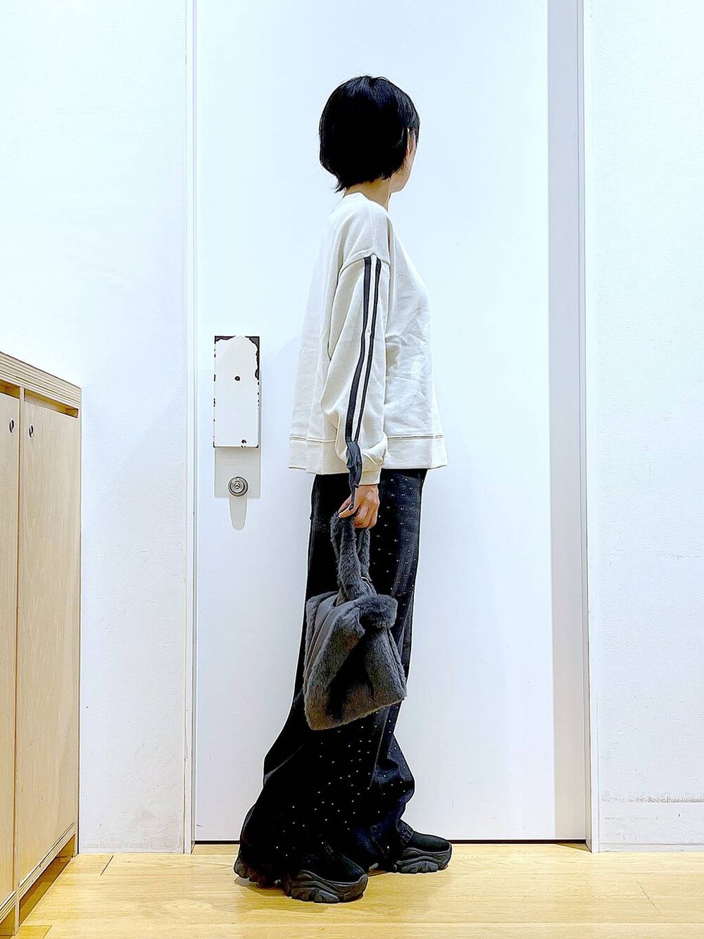 グレー系のショルダーバッグ、ブラック系のブーツ、ベージュ系のスウェットを着用したレディースの秋コーディネートの4枚目の写真