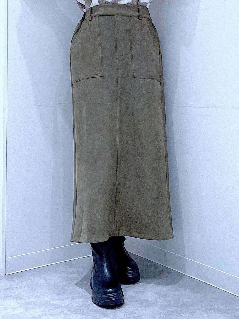 ブラック系のブーツ、ホワイト系のハンドバッグ、グリーン系のスカートを着用したレディースの秋コーディネートの8枚目の写真